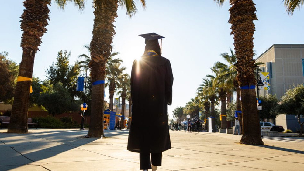 Photo of a College Graduate walking down the Paseo during the morning of Commencement