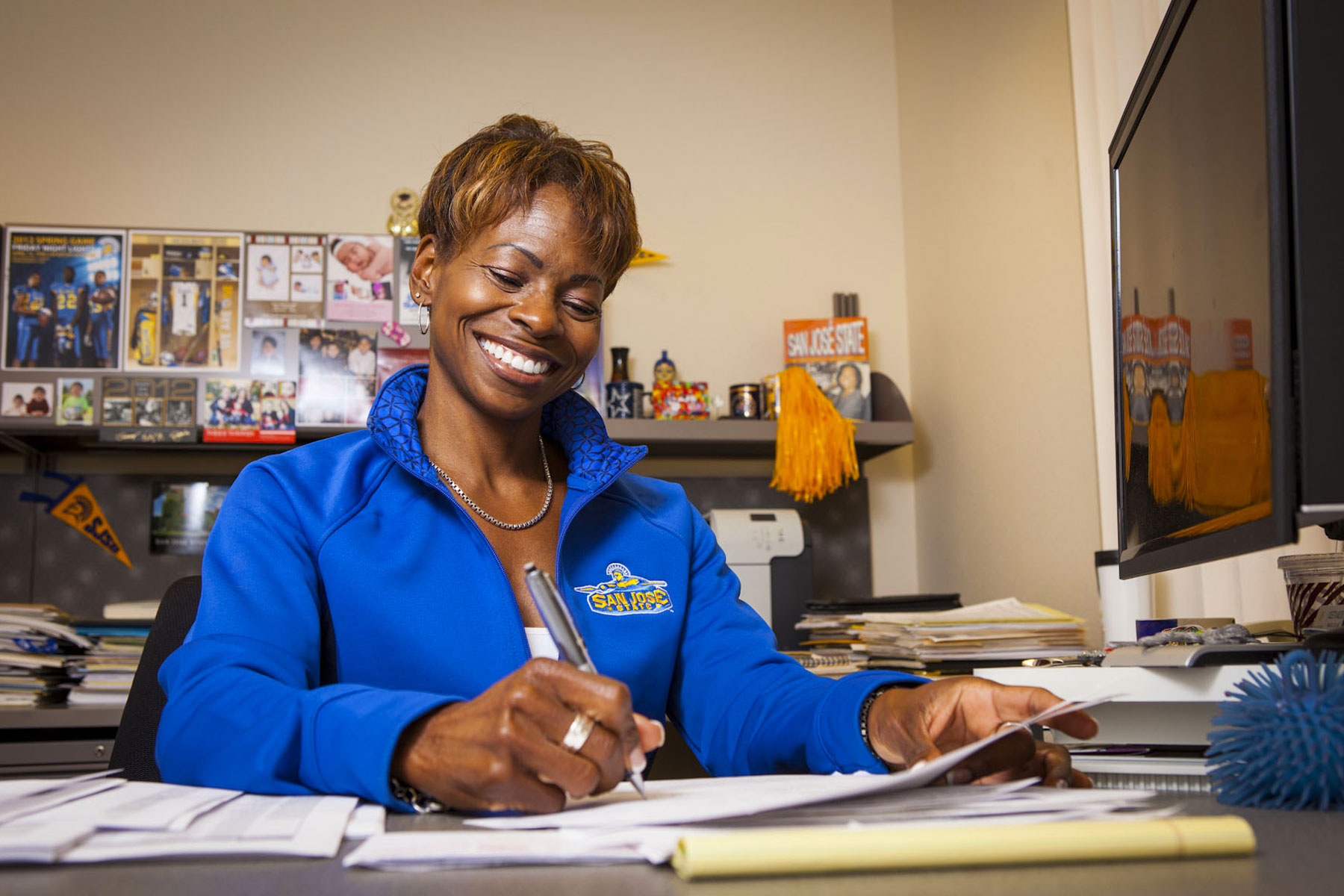 Coleetta McElroy smiling while doing paperwork.