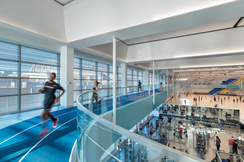 Runners run on 2nd floor track while people lift weights below on the first floor