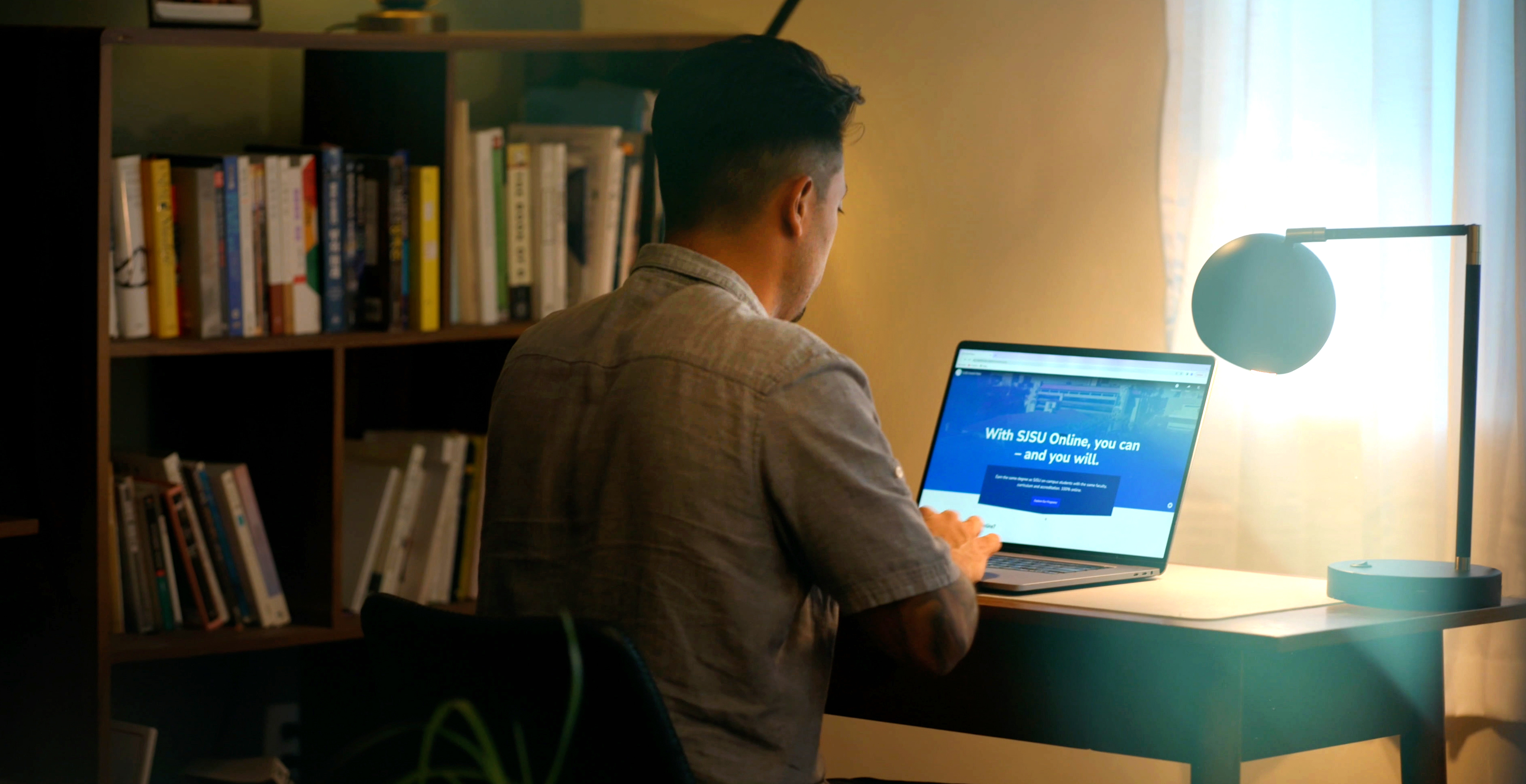 Man looking at SJSU Online homepage in his living room