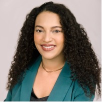 A smiling photo of a woman with light brown skin and long, dark brown curly hair.