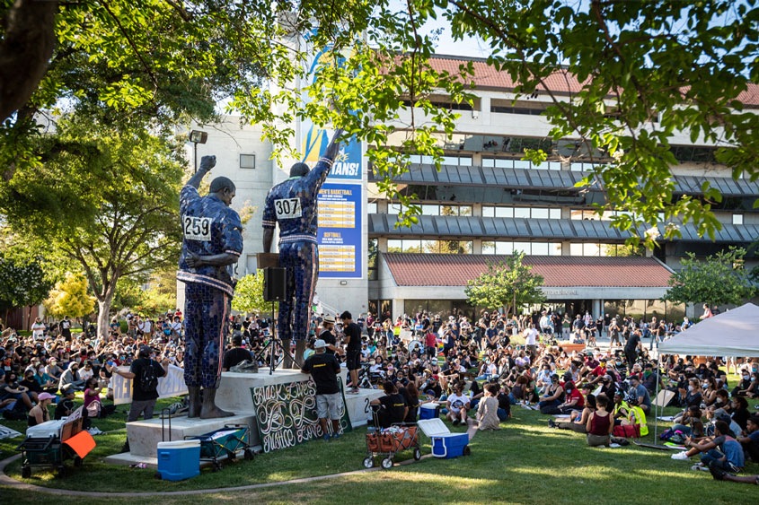 SJSU community members sitting on the lawn during a protest.