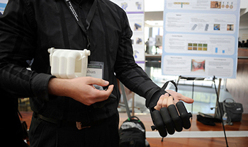 closeup of prosthetic hand on top of real hand with scientific poster in background