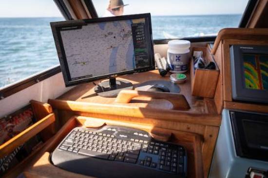 view over computer screen on boat toward ocean. Computer screen maps ocean data