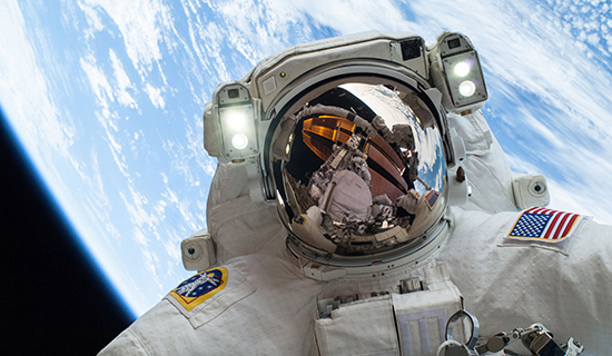 picture of astronaut in space suit, in space with earth and atmosphere in background