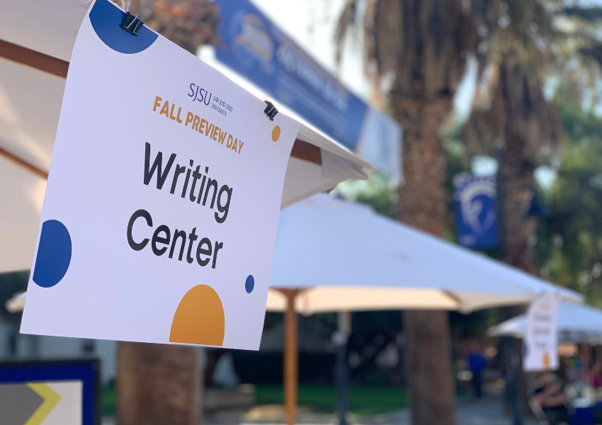 Paper clipped to outdoor umbrella with Writing Center signage